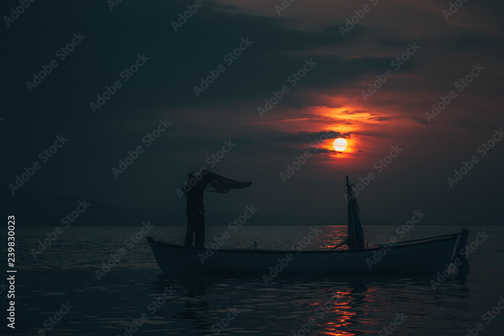 Sun goes down while fisherman throws his fishnet to collect fishes