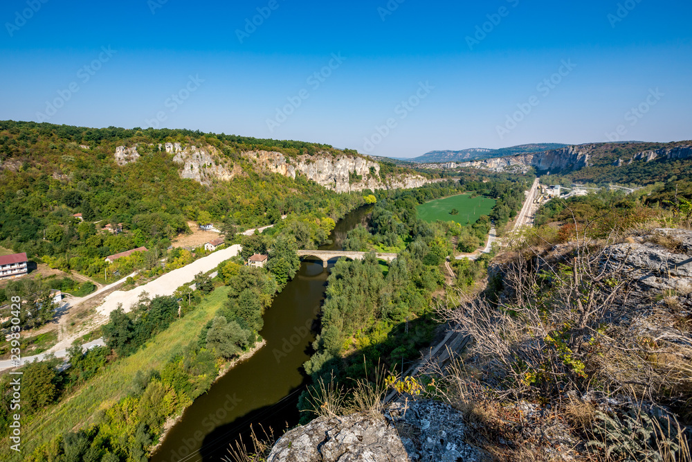 Clear sky autumn day colorful landscape with the big Iskar river near the town and train station Karlukovo in Northern Bulgaria. Beautiful stone bridge across the calm river