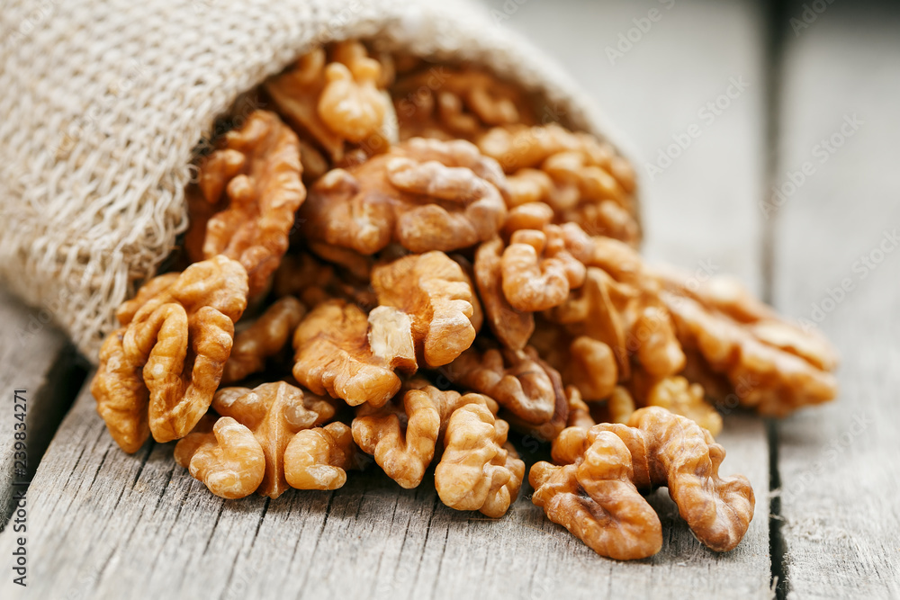 Walnuts in a burlap bag on a wooden gray background. Walnuts in a burlap bag on a wooden gray background.