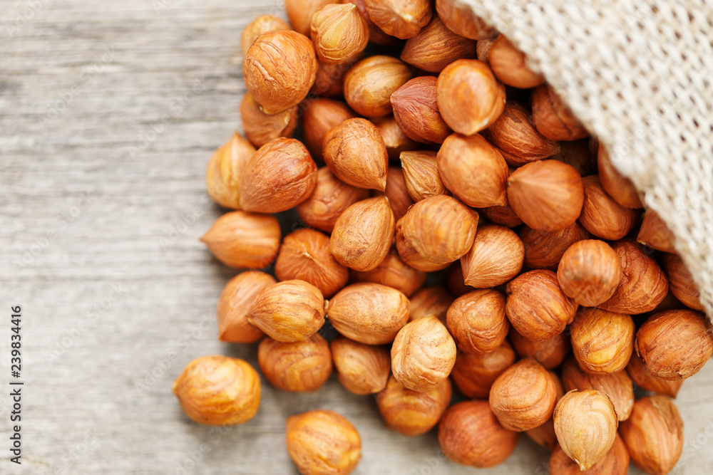 Chiselled hazelnuts in a bag of burlap on a gray wooden table. Organic Fresh Harvested Chiselled hazelnuts in a bag of burlap on a gray wooden table. Organic Fresh Harvested