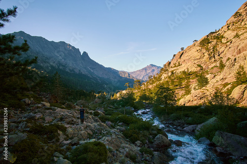 A tourist on a hike in a high altitude alpine valley with a cold stream river in Corsica France mountains GR20