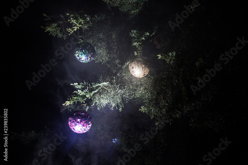 Christmas and New Year decoration on the pine tree branch with lights at the background at night outdoors. Concept of winter holidays.
