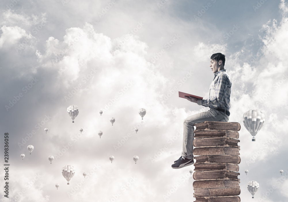 Man student on stack reading book and aerostats flying around Man student on stack reading book and aerostats flying around