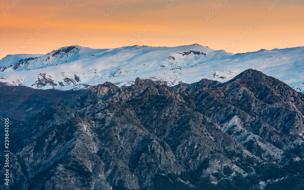 Beautiful sunset with orange tones in the sky and Sierra Nevada snowcapped mountain range , Granada