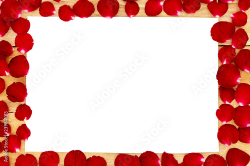 Rose petals arranged in a white frame on a wooden background.