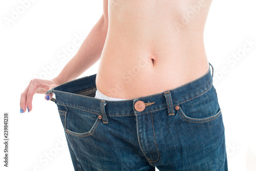 Closeup view of trained belly with big old jeans. Sport, fitness and diet concept. Isolated on white background
