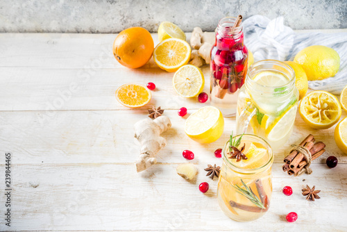 Set of various fall and winter refreshing infused water  sweet sour healthy beverages with oranges  honey  cranberry  mint  rosemary  cinnamon and spices  white wooden background copy space