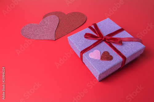 Pink paper gift box and heart shapes on red paper background