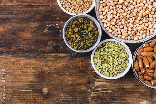 Composition of different types of legumes in bowls on wooden background