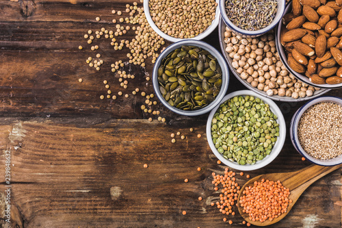 Composition of different types of legumes in bowls on wooden background