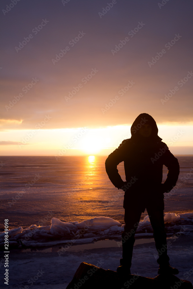 Man on rock on the sea in the ice - silhouette