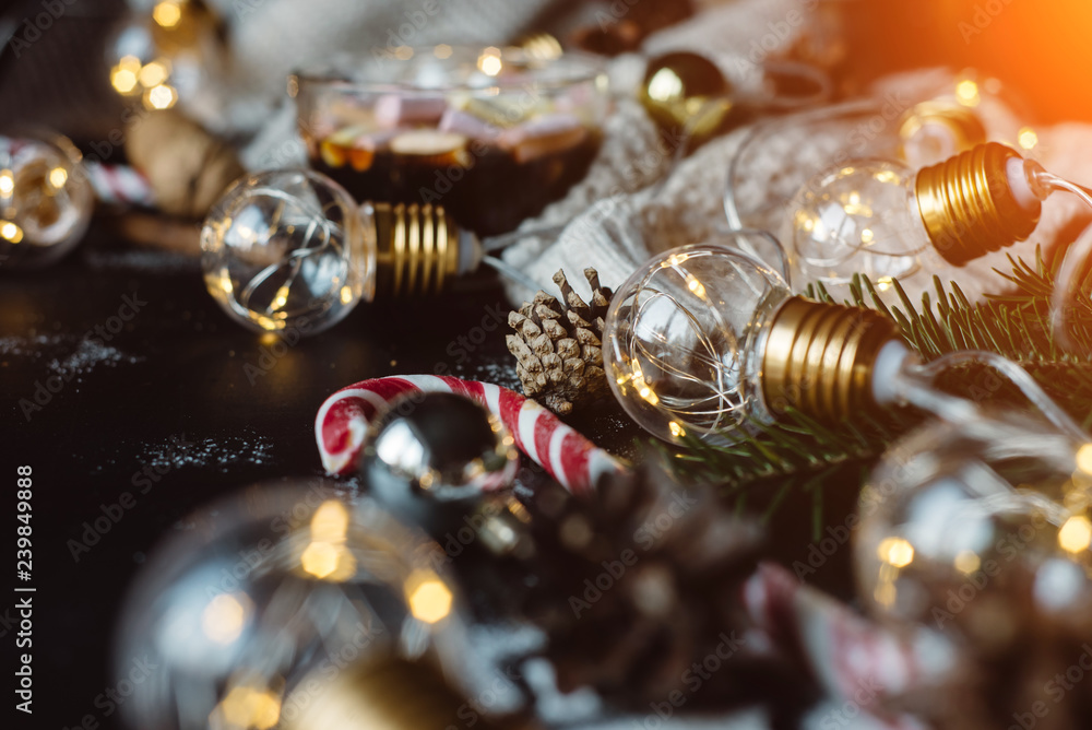 Christmas background with festive decoration, candy and the garland on a dark background with warm rays of the sun. Christmas background with festive decoration, candy and the garland on a dark background with warm rays of the sun.