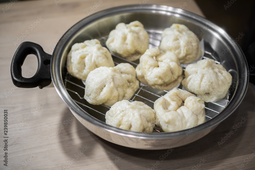 Chinese dumplings (buns) being steamed on a modern stainless steel wok pan Chinese dumplings (buns) being steamed on a modern stainless steel wok pan