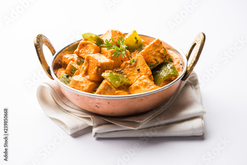 Malai or achari Paneer in a gravy made using red gravy and green capsicum. served in a bowl. selective focus photo