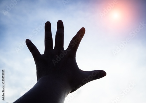 The silhouette humand hand reaching to the sky
