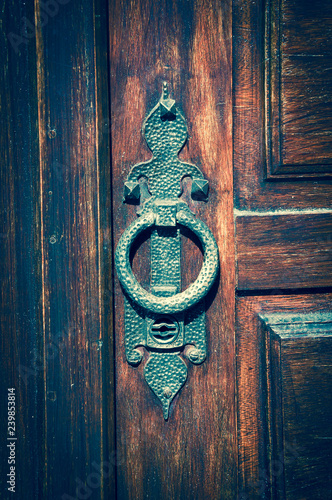 Old shiny brass doorknocker on wooden door.  Retro toned photo. photo