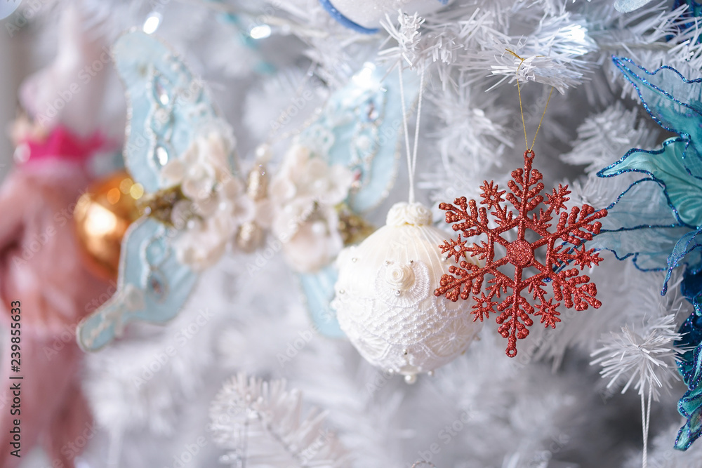 Christmas ornaments. A closed up details of Christmas decoration on a white Christmas tree with soft focus on the glitter snowflake. Christmas ornaments. A closed up details of Christmas decoration on a white Christmas tree with soft focus on the glitter snowflake.