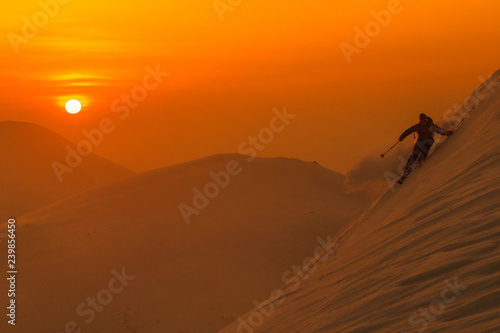 SILHOUETTE  Spectacular shot of pro skier riding off trail on a sunny evening.
