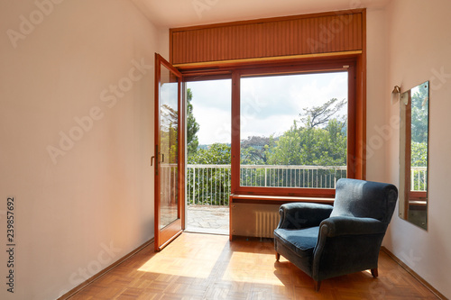 Sunny room interior with terrace and blue velvet armchair in country house