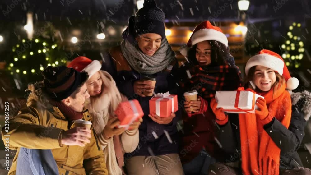 Multiethnic friends in warm clothes drinking coffee and talking in snow street Multiethnic friends in warm clothes drinking coffee and talking in snow street