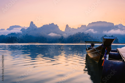 Thai boats at dawn. Boats at the pier. Lake Cheo LAN in the national Park Khao SOK in Thailand . Mountains and clouds in the background. Dawn over the jungle