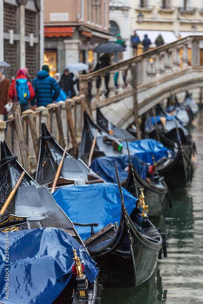 Parked gondolas at side canal at rainy day in Venice, Italy