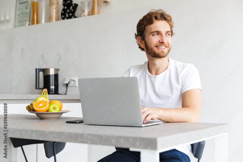 Young bearded man at the table at home talking using laptop computer. Young bearded man at the table at home talking using laptop computer.
