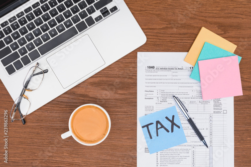 top view of tax form  coffee  laptop and blue card with  tax  word on desk