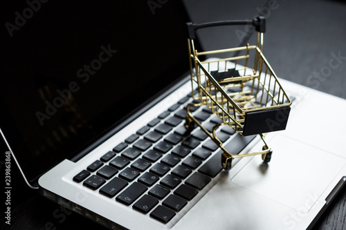 Online shopping bank card nearby a laptop and mini shopping cart