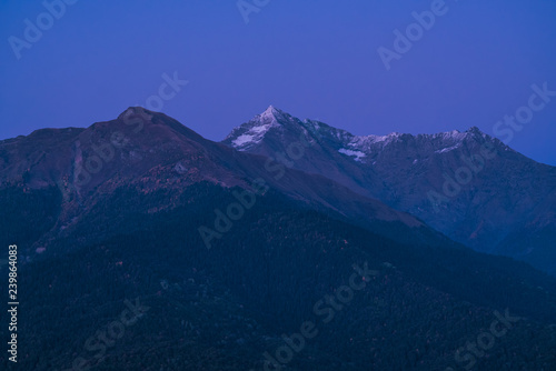 Mountains in the sunset light. Purple peaks and dark blue sky. Snow on mountain peaks