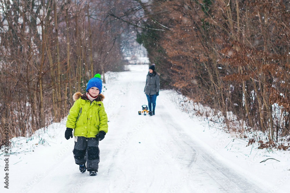 Happy little boy on winter walk. Happy child with mother having fun outdoors. Enjoying spending time together. Beautiful snowy winter park. Family holidays in snowy winter walk. Snowy weather. Happy little boy on winter walk. Happy child with mother having fun outdoors. Enjoying spending time together. Beautiful snowy winter park. Family holidays in snowy winter walk. Snowy weather.