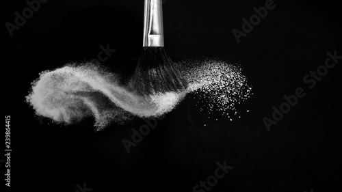 Cosmetic brush with white cosmetic powder spreading for makeup artist or beauty blogger in black background