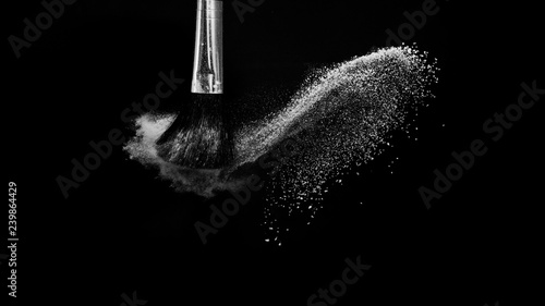 Cosmetic brush with white cosmetic powder spreading for makeup artist or beauty blogger in black background