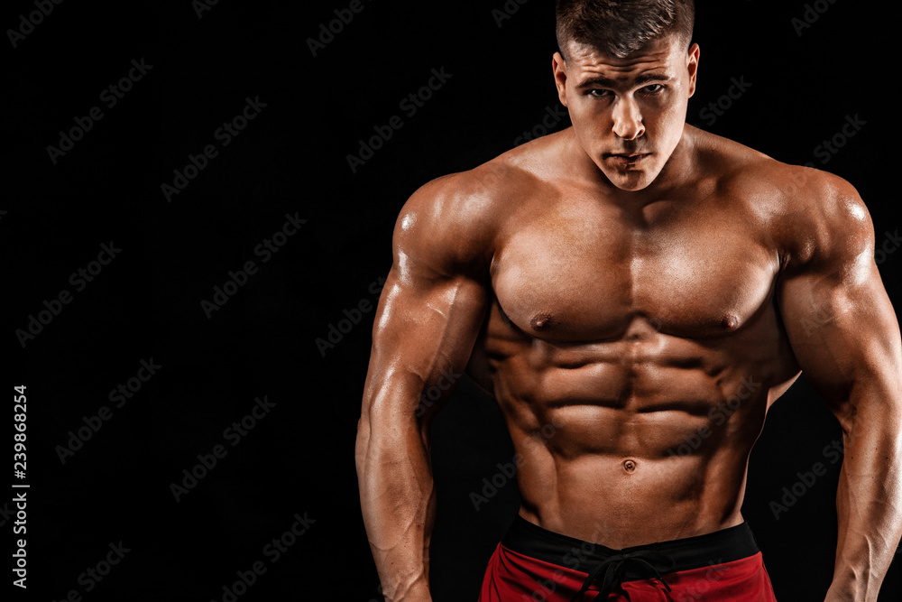 Brutal strong muscular bodybuilder athlete man pumping up muscles on black background. Workout bodybuilding concept. Copy space for sport nutrition ads.