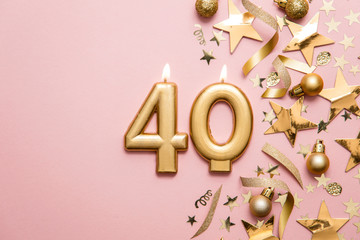 Number 40 gold celebration candle on star and glitter background