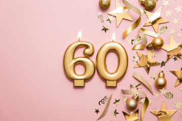 Number 60 gold celebration candle on star and glitter background