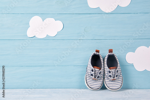 Baby boy shoes on a blue wooden background with clouds photo