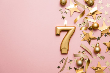 Number 7 gold celebration candle on star and glitter background