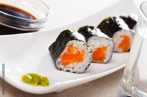Maki rolls with salmon served with wasabi and soy sauce on white plate