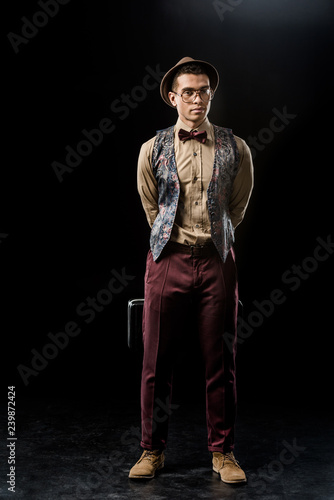 confident young male jazzman posing with trumpet case on black © LIGHTFIELD STUDIOS