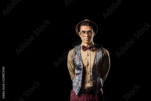 stylish young male model in vest and bow tie posing isolated on black