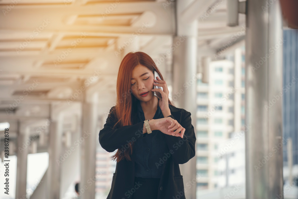 Time out concept. Urgent work, business woman seeing wrist watch and using mobile phone before meeting. Smart woman check the schedule before going to the office. Time out for appointment meeting. Time out concept. Urgent work, business woman seeing wrist watch and using mobile phone before meeting. Smart woman check the schedule before going to the office. Time out for appointment meeting.