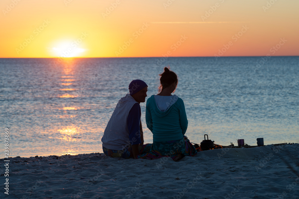 Fototapeta premium Romantic couple relaxes on a beach, drinks coffee