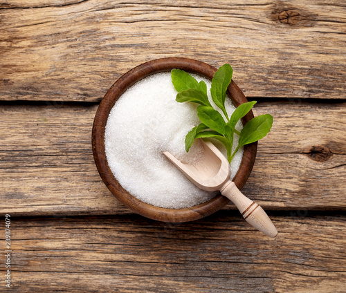Stevia rebaudiana, sweet leaf sugar substitute isolated in wooden bowl on wooden background photo