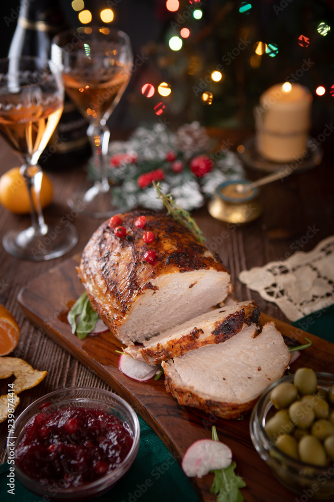 Sliced pork lies on a festive table with New Year's décor and Christmas lights in the background Sliced pork lies on a festive table with New Year's décor and Christmas lights in the background