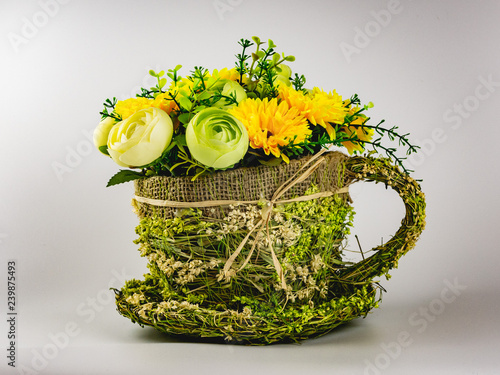 yellow-green bouquet of artificial flowers in a straw pots on a white background