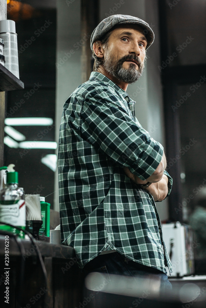 Calm bearded man having arms crossed and looking into the distance