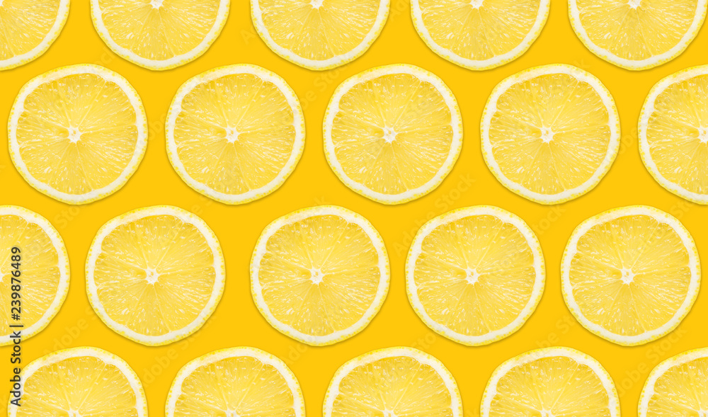 Yellow lemon slices pattern isolated on empty yellow surface with decorative shadow. Vibrant fruit background.