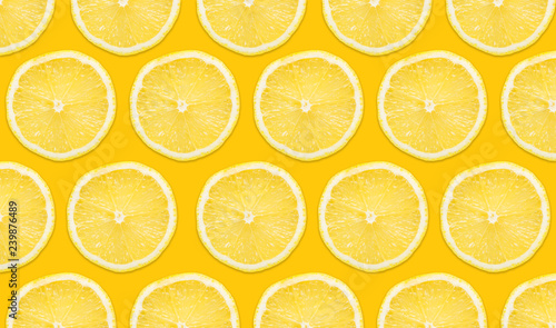 Yellow lemon slices pattern isolated on empty yellow surface with decorative shadow. Vibrant fruit background.