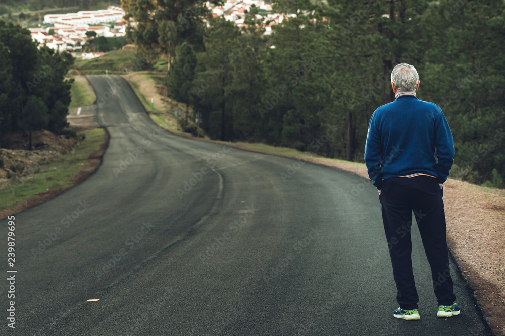 Older man of back standing on lonely highway Older man of back standing on lonely highway